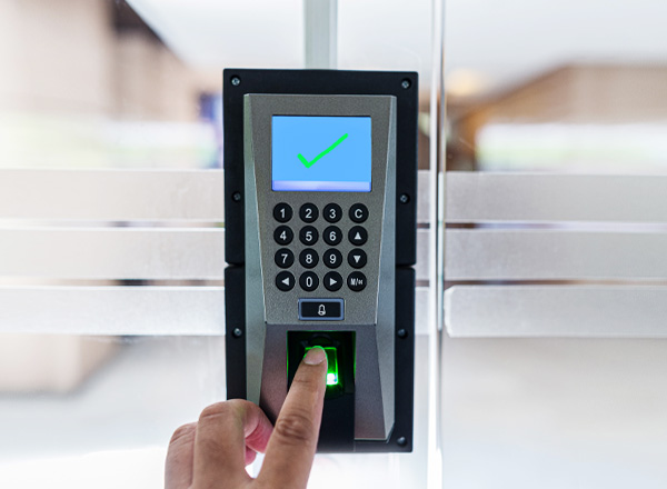 A person's hand using a security touchpad on a glass door