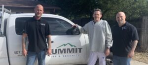 Three people standing next to a Summit company pickup